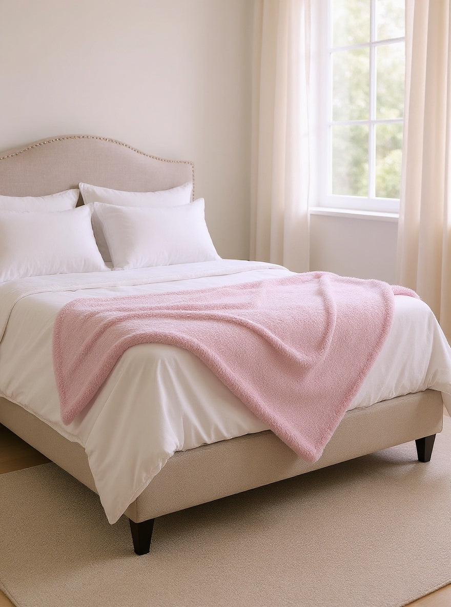 Plaid rose plié au pied du lit — chambre lumineuse