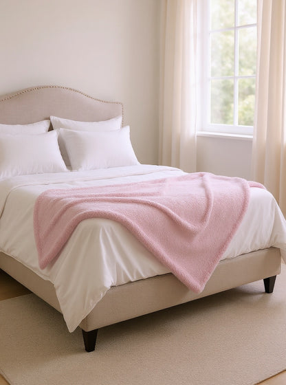 Couverture polaire rose au pied du lit